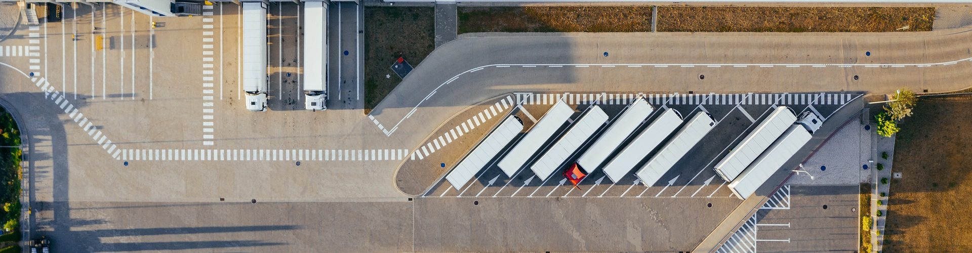 Bild av marcinjozwiak från Pixabay tagen ovanifrån där flera bilar och lastbilar står parkerade i rutor.